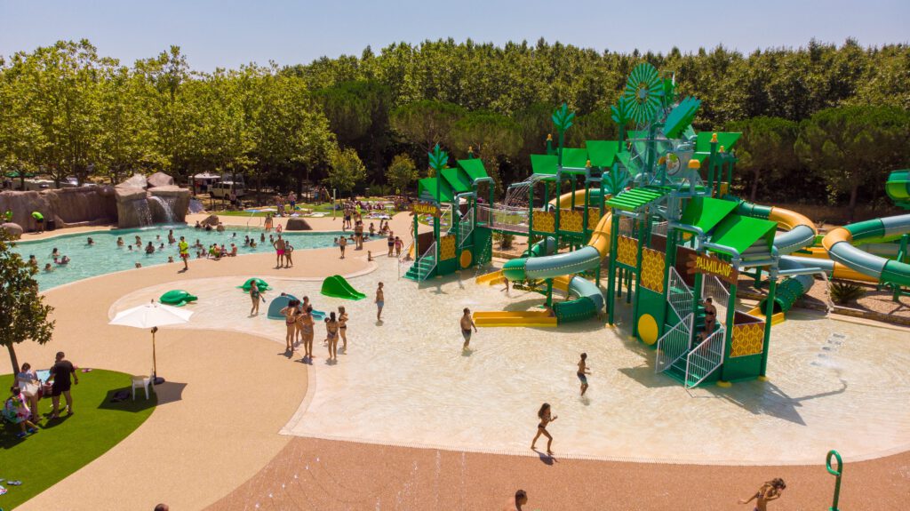 Water play area with green slides beside a curved pool