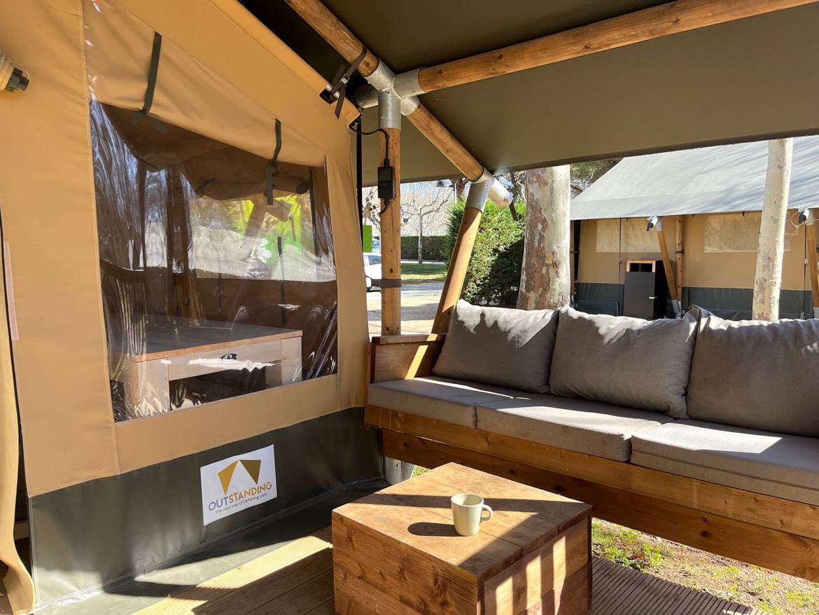 Kenia Lodge Tent 16 m² without bathroom: Covered terrace with cushioned seating and a low table